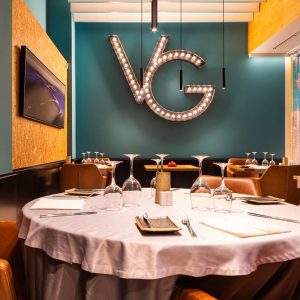 Round restaurant table with bright colours on the wall and a VG sign