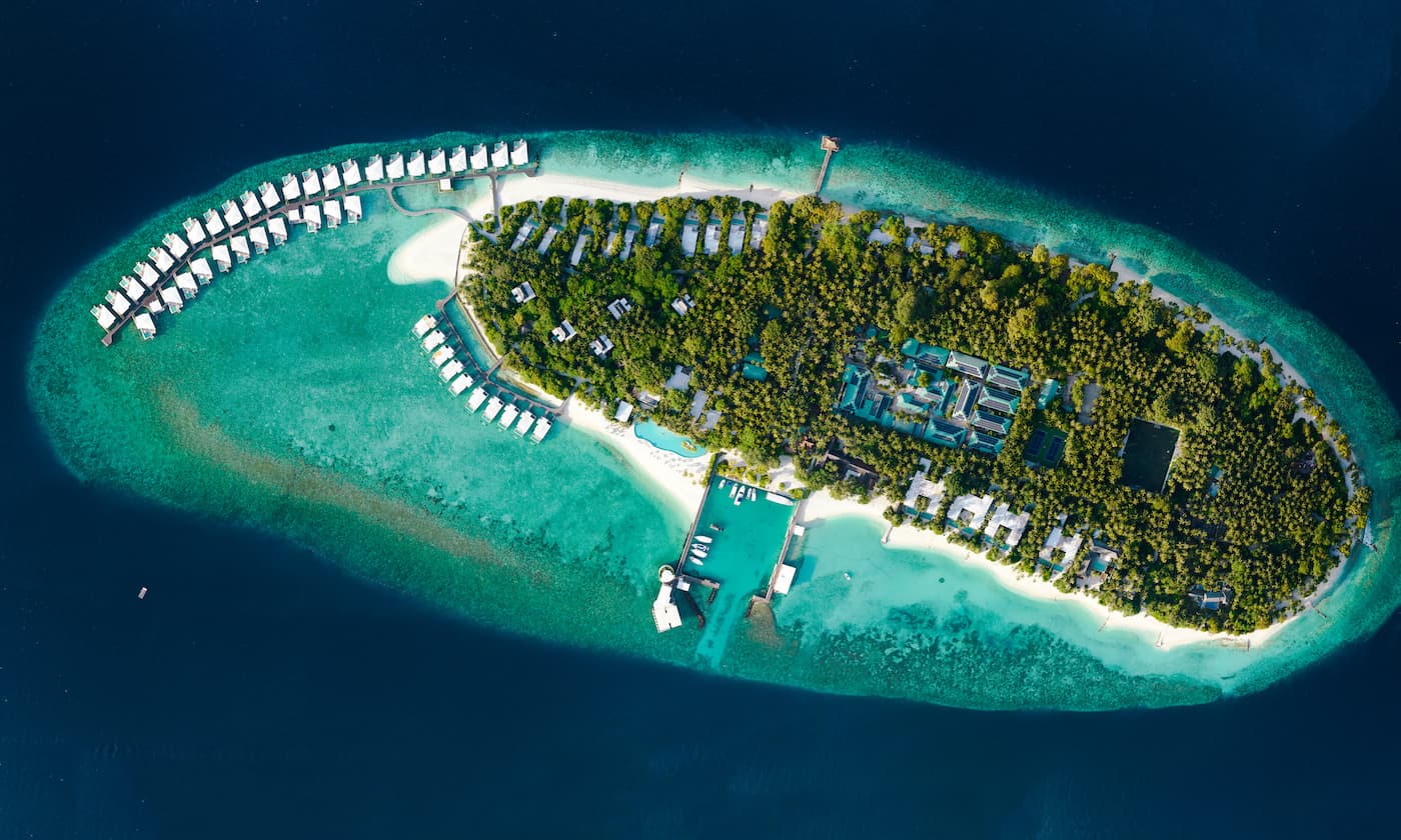 An aerial shot of Amilla island. You can see the water villas jutting out to the side and various facilities dotted around the isalnd